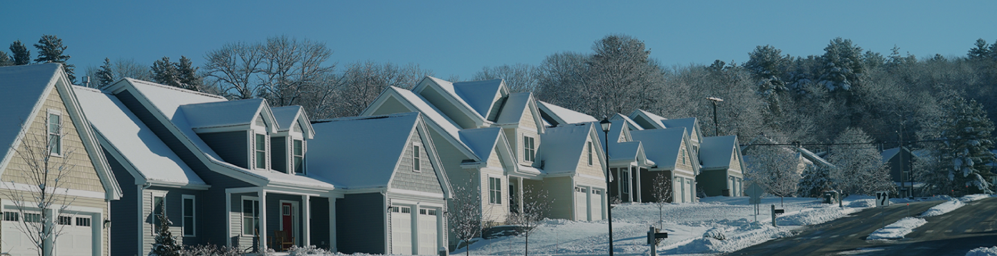Many houses on a snow filled street with snow on the roof's